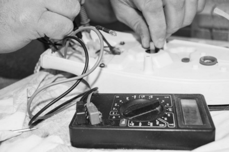 黑白照片, 特写老电工手, 使用数字电压表来修复电熨斗, 选择性对焦