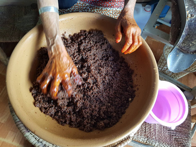 女人在一个陶罐里混合了从阿根油生产出来的蛋糕。化妆品原料..