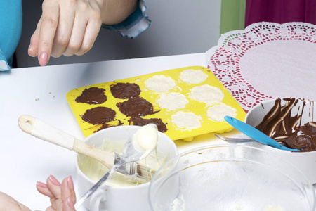一个女人涂巧克力填充椰子和炼乳。 甜点的配料在桌子上。 用椰子和炼乳烹饪糖果。 在白色和黑色巧克力的釉里。