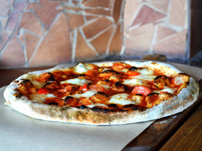 意大利比萨饼与培根番茄草药从烤箱在木板上供服务。 快关门。 披萨餐厅的概念。