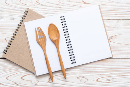 空白笔记本，用于木制表面的文字笔记，木制勺子和叉子，带有复制品