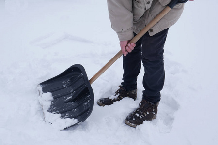 男人在冬天的暴风雪中扫除铲雪