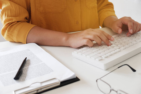 闭上女性的手。 穿休闲布的女性在办公室里用键盘打字。