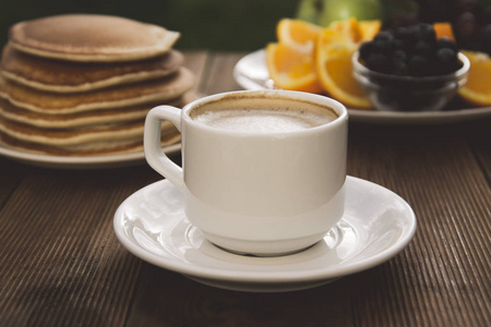 健康的早餐。美味的自制美国煎饼，配咖啡和水果。木制桌子，美丽的早晨