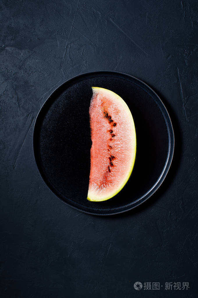 黑色盘子上的一片西瓜深色背景顶部视图