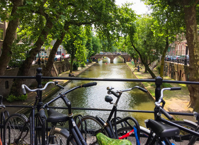 自行车站在桥上，在阳光明媚的日子里，在荷兰乌得勒支的老运河和街道上看到了令人惊叹的景色