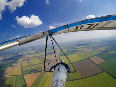 一望无际悬挂滑翔机飞行员飞得很高,飞过一望无际的绿色田野.