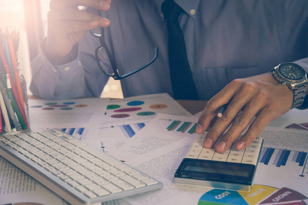 商人或会计师从事计算器计算商业数据概念。 会计投资顾问对财务报告的咨询情况，并在办公室规划营销计划。