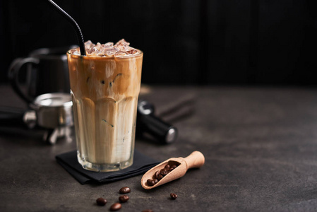 冰咖啡，奶油在一个高玻璃和咖啡豆，波特法尔特篡改和牛奶罐在黑暗的混凝土桌子上，黑色的木制背景。 冰凉的夏日饮料。 复制文本空间。