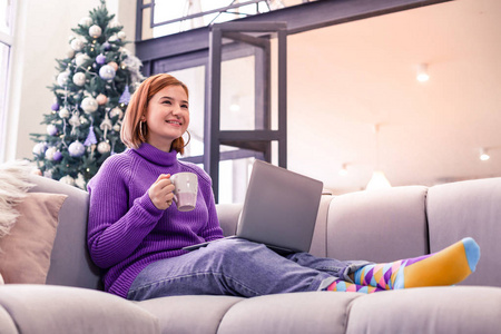 色毛衣漂亮的年轻红头发的微笑的女孩在紫罗兰色毛衣放松在家里照片