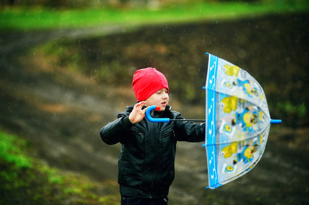 一个小男孩的肖像，带着一把伞在春天的散步中