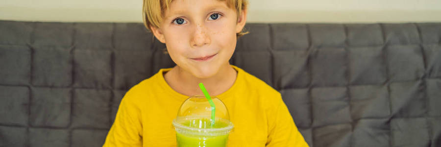 这个男孩正在喝绿茶拿铁和杯子里的冰。自制冰抹茶带牛奶零废料横幅, 长格式