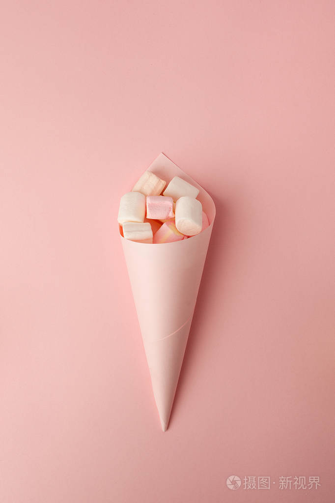 棉花糖糊状颜色分类在纸锥上的粉红色背景从上面看. 糖果变异.