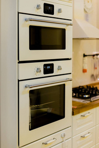 优雅的厨房内饰配有白色灰色家具。厨房的现代化内饰, 配有电炉和烤箱。厨房里有花纹瓷砖地板和墙壁。现代厨房的垂直视图