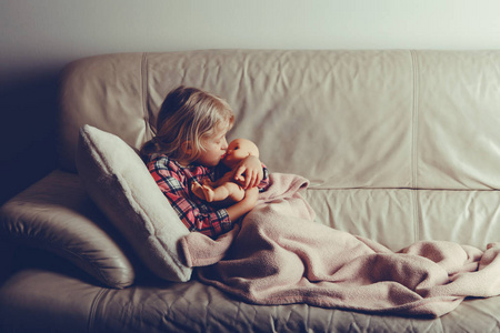 孩子玩玩具。 可爱的高加索女孩抱着拥抱亲吻娃娃。 孩子晚上躺在床上，晚上晚上躺在室内。 与胶片过滤器风格色调。 快乐的童年生活方