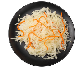 在白色背景上分离的黑色盘子中腌制的卷心菜和胡萝卜。 顶部视图