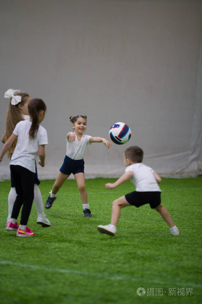 小孩子们在球场上踢皮球踢球笑着踢足球