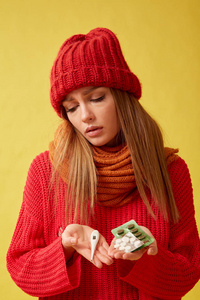 生病的女人拿着医用温度计和药丸。 黄色背景图像