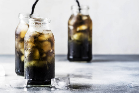 健康的食品和饮料概念玻璃瓶中含有碎冰的冷黑排毒矿泉水活性炭灰色石桌背景时尚饮料复制空间选择性聚焦