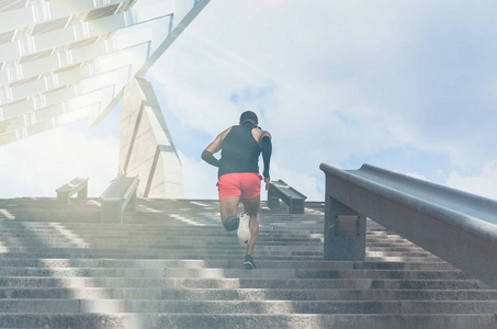 肌肉高加索年轻的男性深色皮肤运动员跑上楼梯与速度, 运动的年轻人在黑色 t恤训练或在户外锻炼, 而慢跑的步骤。后视图