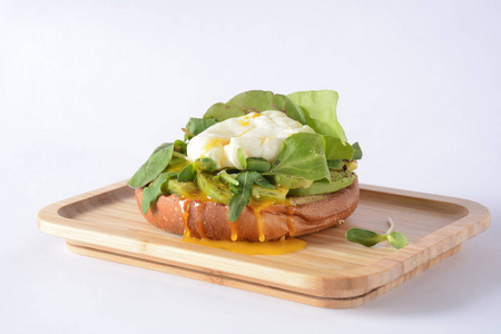 韭菜煮鸡蛋。 桌子上的木制盘子。 用面包鳄梨和甜菜叶在三明治上挖鸡蛋。 健康均衡早餐的概念