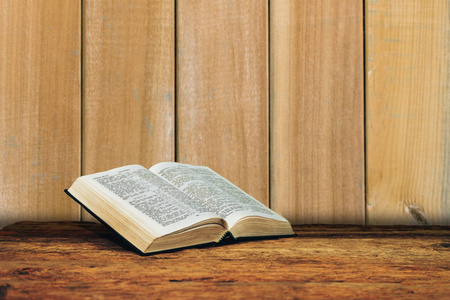 圣经在一个旧的木制桌子背景上。