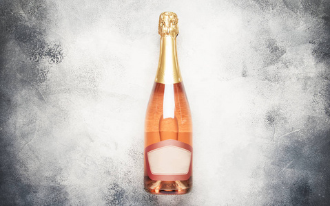 带粉红色起泡葡萄酒或玫瑰香槟的瓶子，灰色背景，带文字假期或约会概念的地方，平躺在顶上看