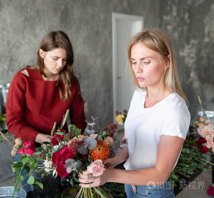 花店工作场所。妇女安排与玫瑰, 菊花, 康乃馨和其他花花束。大师班或课程中的花卉教师和学生