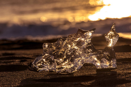 冰岛东南部的Jokulsarlon海滩钻石海滩上有黑色沙滩的冰崖。 太阳升起时的冰