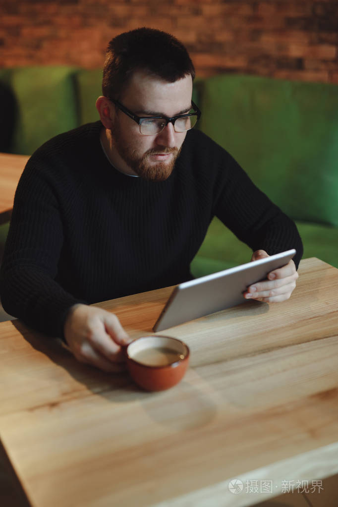 在平板电脑工作的人在商务午餐期间喝咖啡