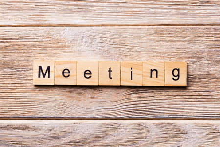 在木块上写的会议字。 会议文本在木桌上为您的设计概念。