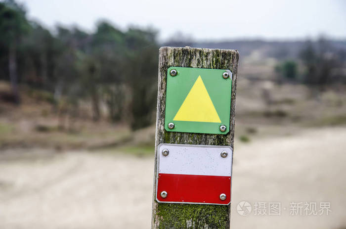 荷兰杜宁国家公园的木杆，带有绿色黄色箭头标志和红色白色长途小径标记