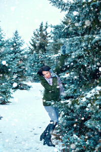 美丽的女人在冬天的森林里，绿杉树和雪