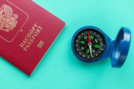 绿色木制背景上的指南针和护照。