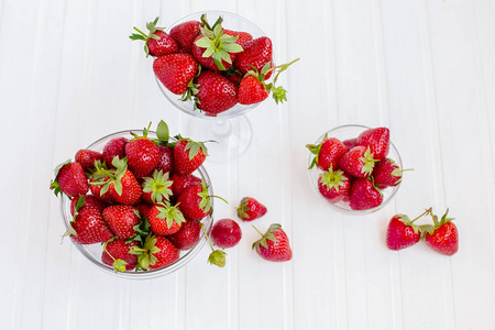 白色木制桌子上的玻璃碗里的红色成熟草莓。 从你的花园收获。 健康饮食的概念。