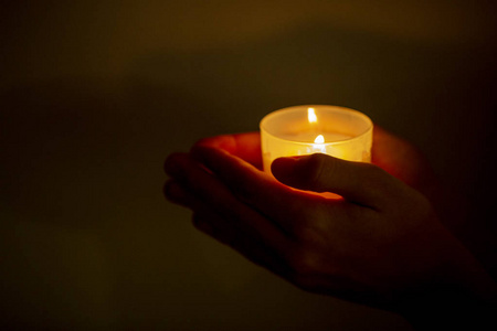 在黑暗中拿着蜡烛的手照片