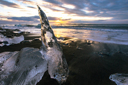 冰岛东南部的Jokulsarlon海滩钻石海滩上有黑色沙滩的冰崖。 太阳升起时的冰