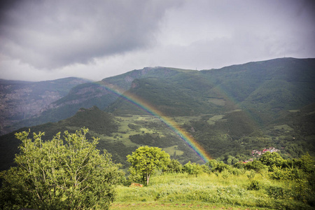 在亚美尼亚塔特夫苏尼克省的山上彩虹。 带亚美尼亚教堂的山地景观