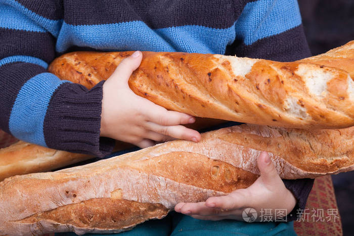 小男孩拿着一捆法国面包. 烘焙和烹饪概念背景. 手拿新鲜面包照片-正