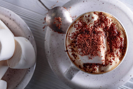 热巧克力和棉花糖洒在白色木桌上的巧克力片。