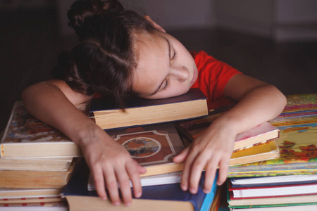 睡觉的女孩带着一堆书，把注意力集中在前景上