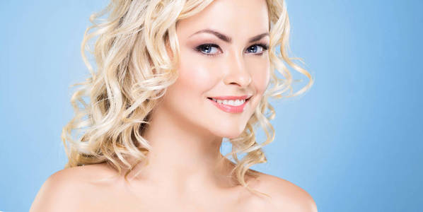 漂亮的金发女人的美丽肖像，卷发和美丽的发型。 化妆和化妆品的面部提升和美容概念。