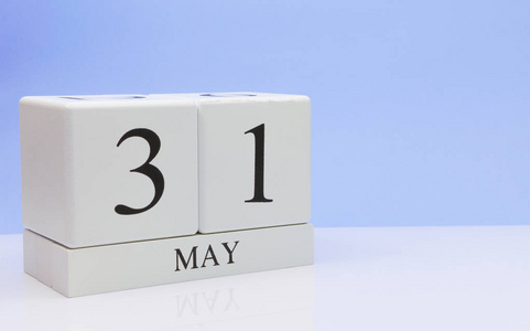 月31日每日日历在白色桌子上,反射浅蓝色背景.