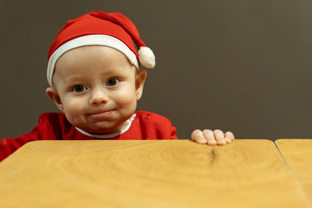 滑稽的男婴在圣诞老人帽子举行的桌子
