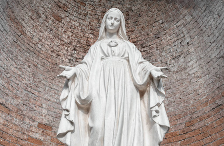 圣母玛利亚石上的雕像。 背景红砖墙上。 理想的圣诞节和复活节概念和其他。