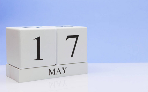 月17日每日日历在白色桌子上,反射浅蓝色背景.