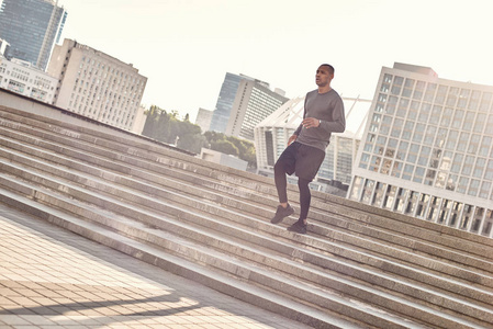 运动在我的生活中。在阳光明媚的温暖天气里, 穿着运动服在城市环境中慢跑楼梯的非洲运动员的全长画像。有氧运动训练