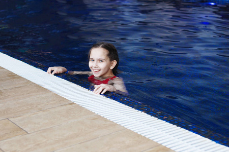 泳池里的年轻女孩，蓝色的水，突出前景