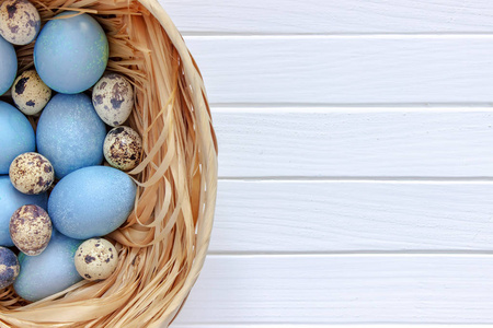 复活节彩蛋放在一张白色木桌上的篮子里。顶视图