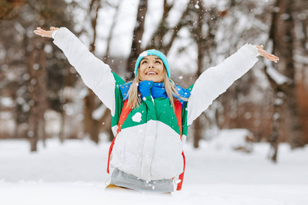 快乐美丽的年轻女子在一天的冬季吹雪花从她的手